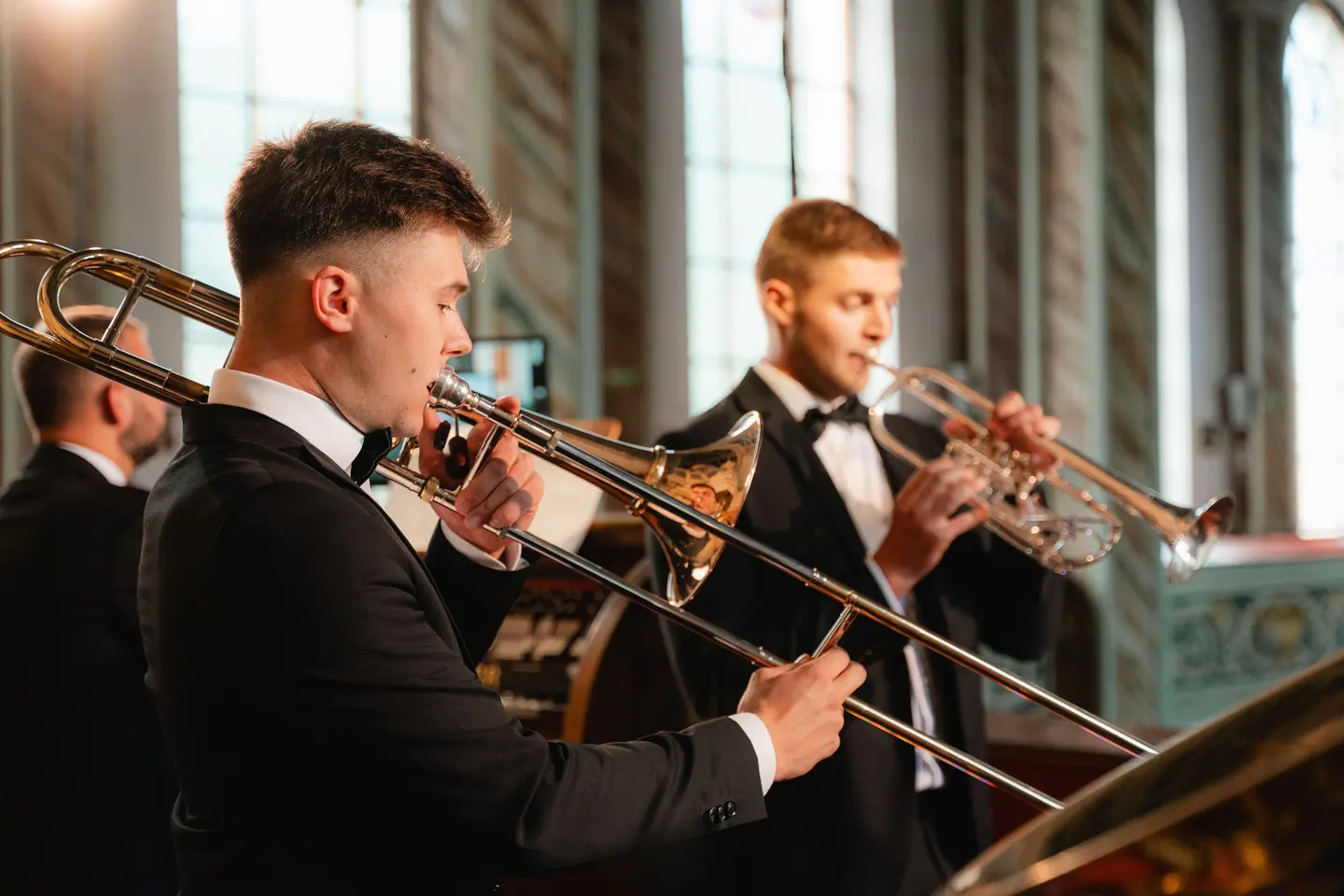Muzycy Silver Brass grający na puzonie i trąbkach przy pulpitach w kościele